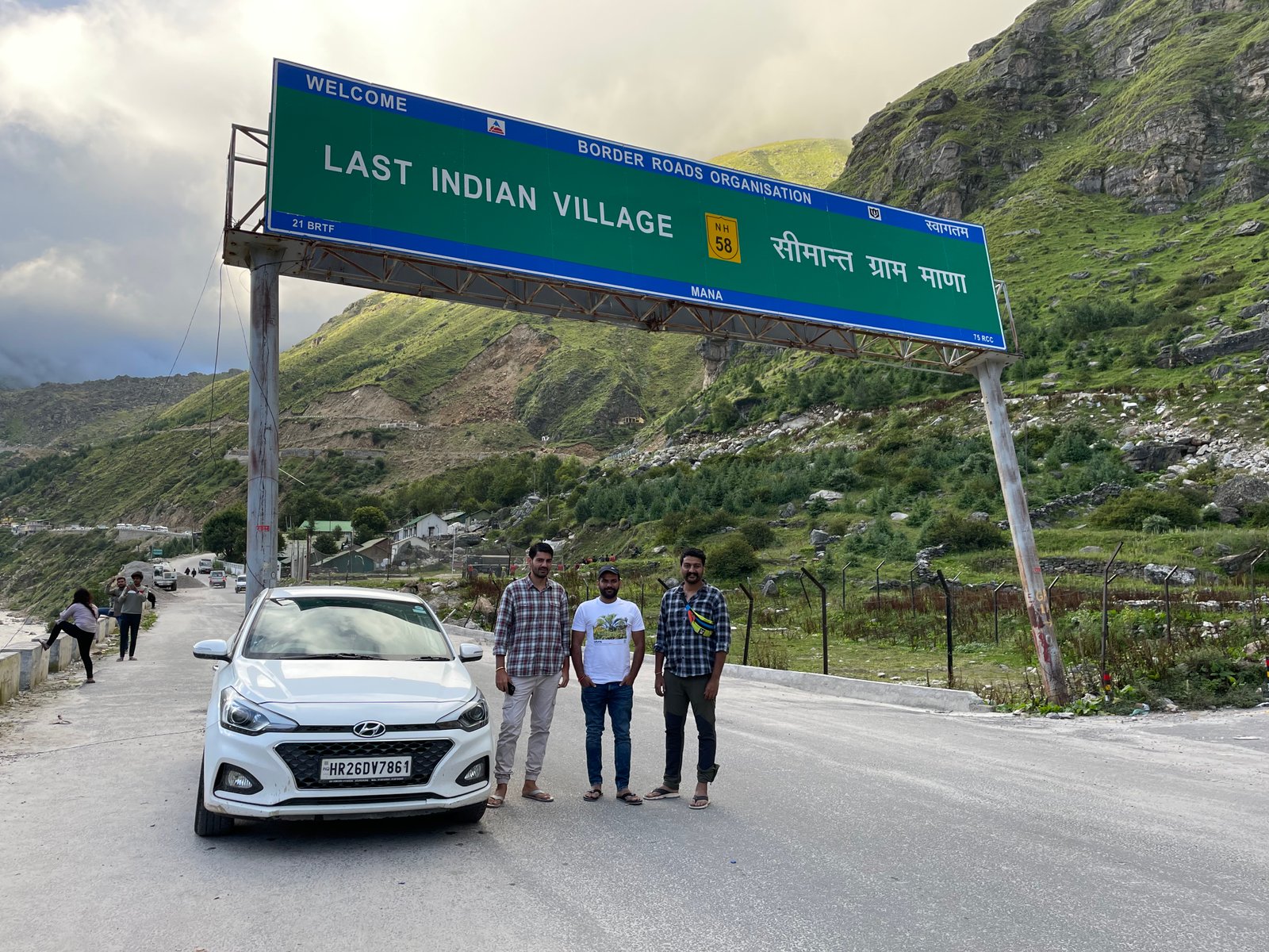 Naveen Kumar and friends beneath the Last Indian Village sign at Mana