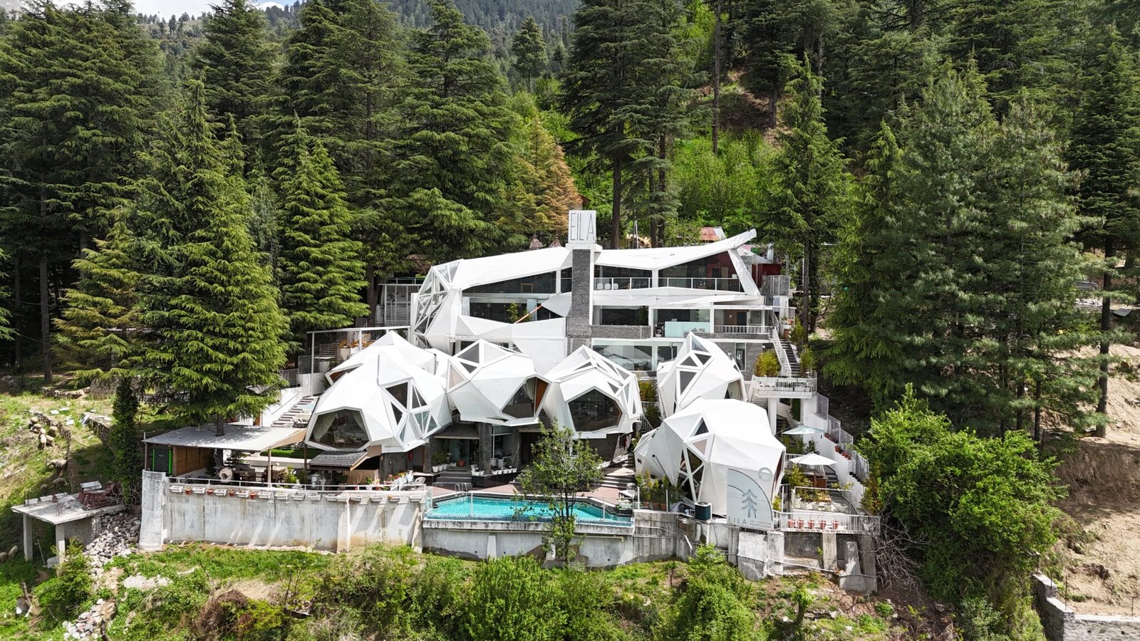 Aerial view of Tree of Life Eila Art Hotel on a green hillside in Naggar