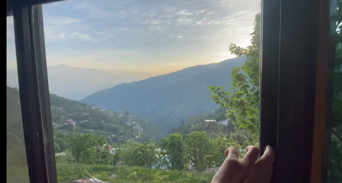 Green hillside and valley seen through the Amar Homestay room window near Narkanda