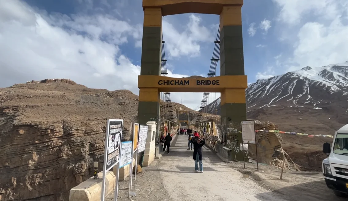 Chicham Bridge entrance with visitors and snow-covered mountains