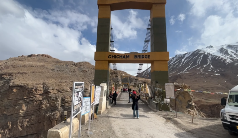 Chicham Bridge entrance on a Kaza circuit with visitors and snow-covered mountains