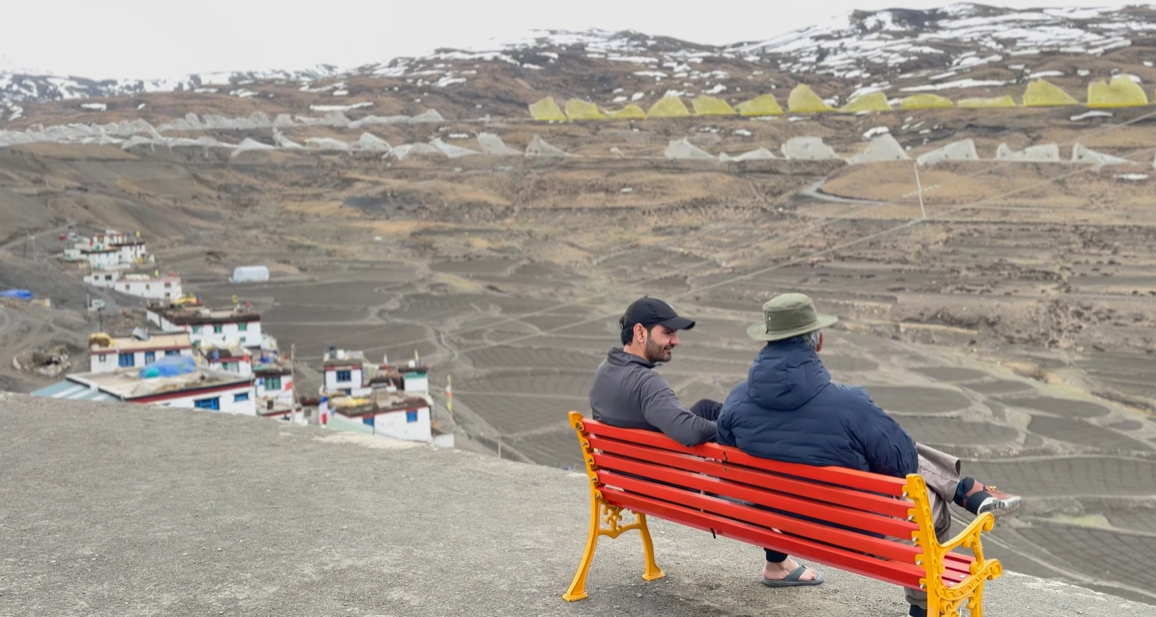Kaza one day trip view from Komic village with two travellers on a red bench