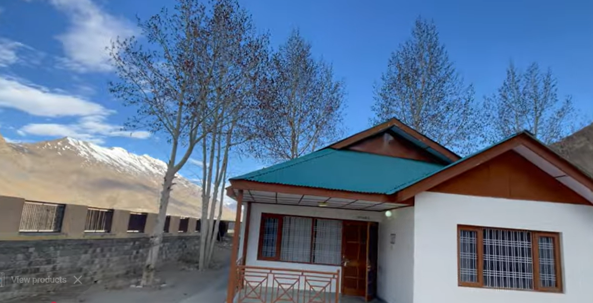 Cottage at Hotel The Spiti Kaza with blue roof, trees and mountains