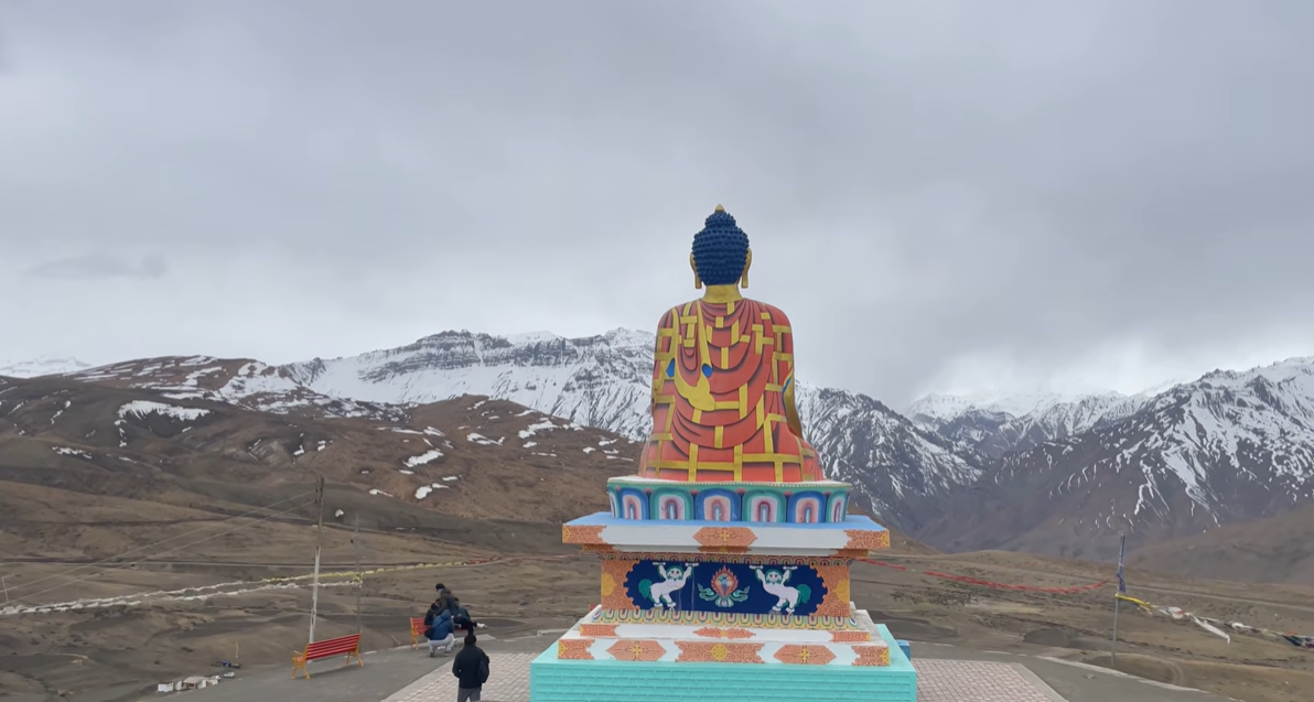 Rear view of the Langza Buddha statue facing snow-covered Himalayan mountains