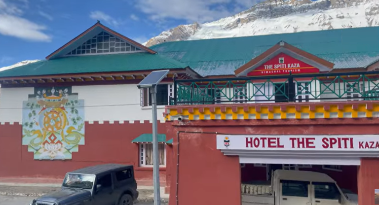 Hotel The Spiti Kaza entrance with parked vehicles and snowy mountains