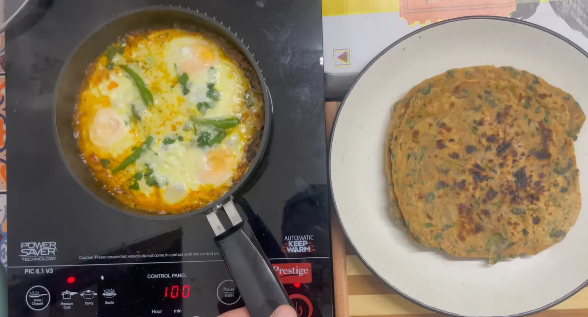 Finished cheesy egg shakshuka beside a plate of methi parathas