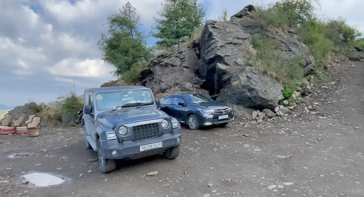 Cars parked on the rough hillside parking area at Gadegal Homestay