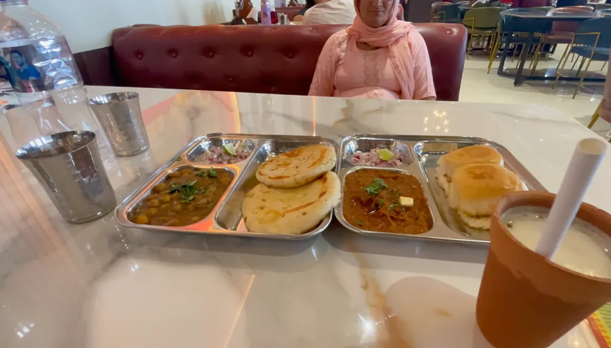 Two stainless-steel meal trays and a clay cup on our table at Moga Haveli