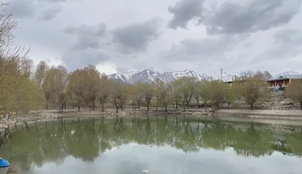 Nako Village travel guide view of the lake reflecting trees and snow-covered mountains