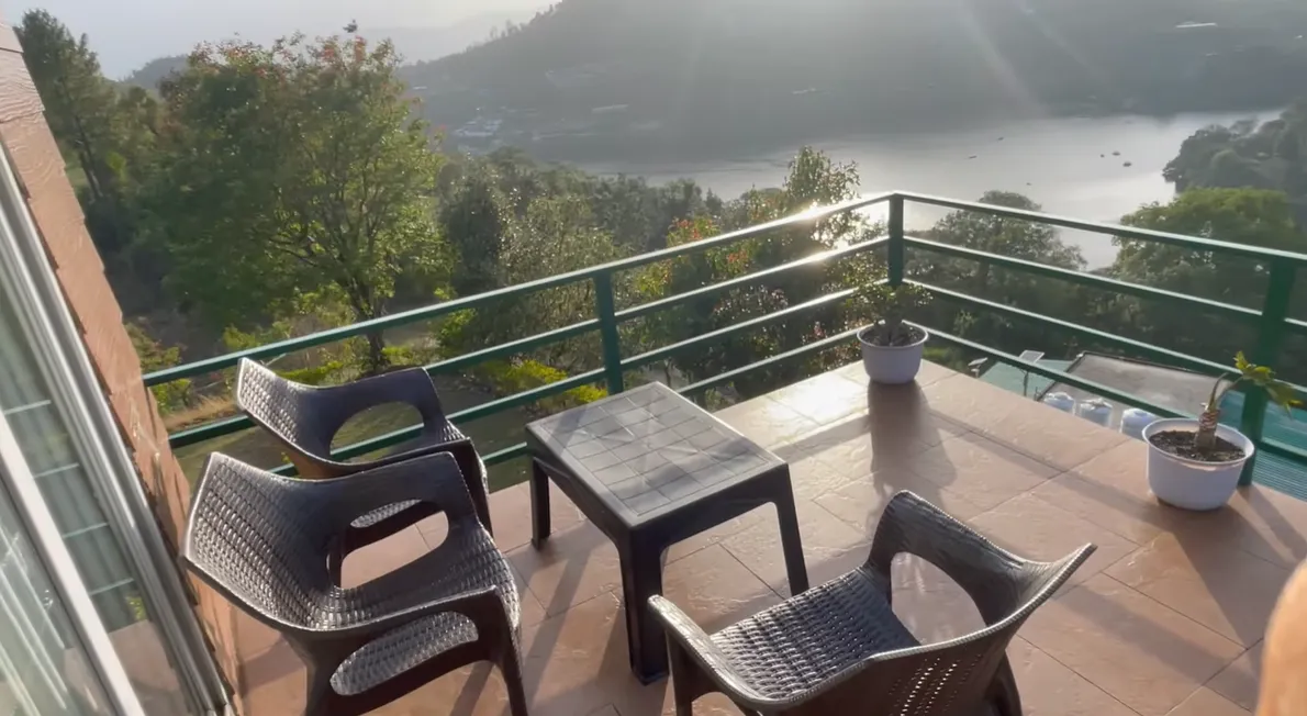 Chairs and tables on the suite balcony overlooking Naukuchiatal Lake