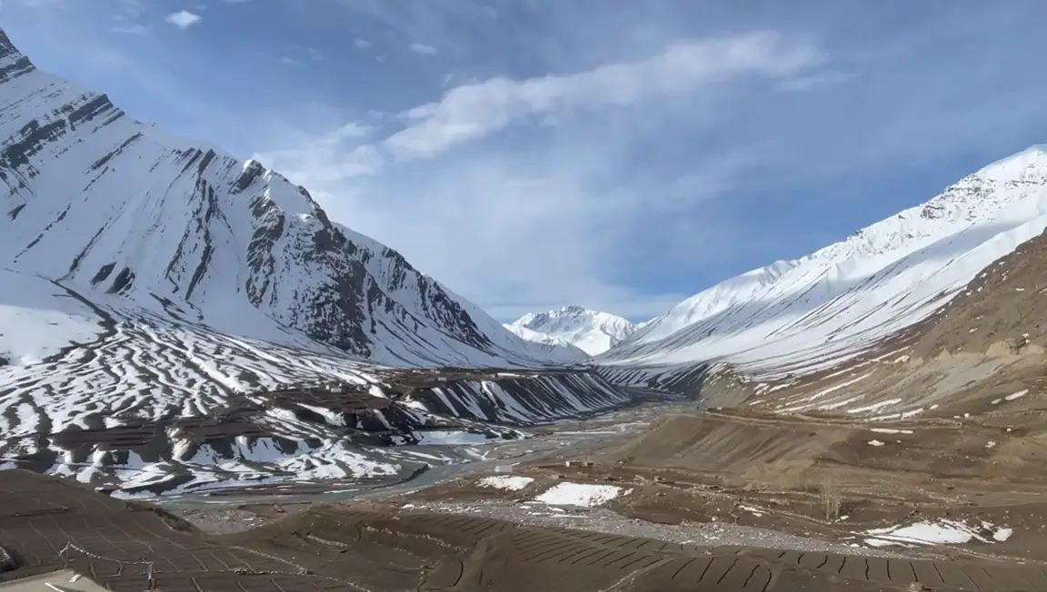Snow-striped mountains, riverbed and fields viewed from Mudh village in Pin Valley