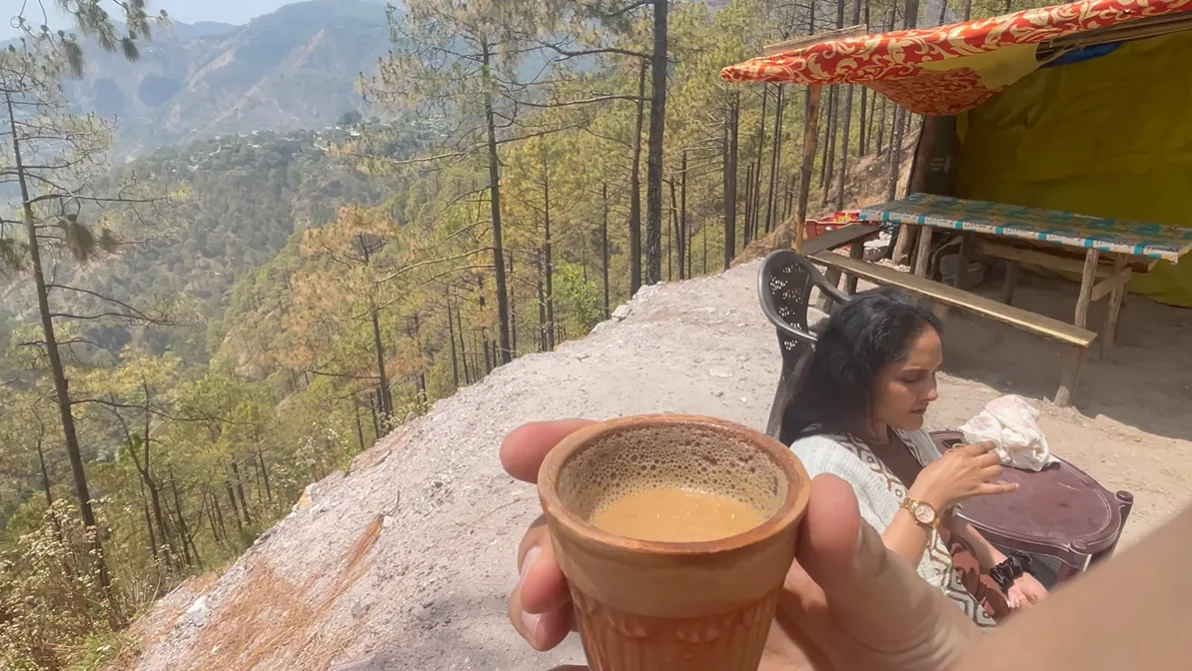 Clay cup of tea at a roadside stall overlooking pine-covered Uttarakhand hills