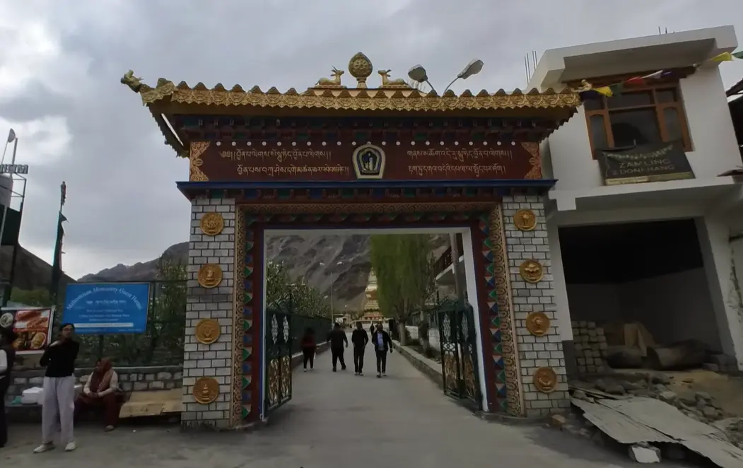 Ornate entrance gate to Tabo Monastery with visitors walking into the complex.