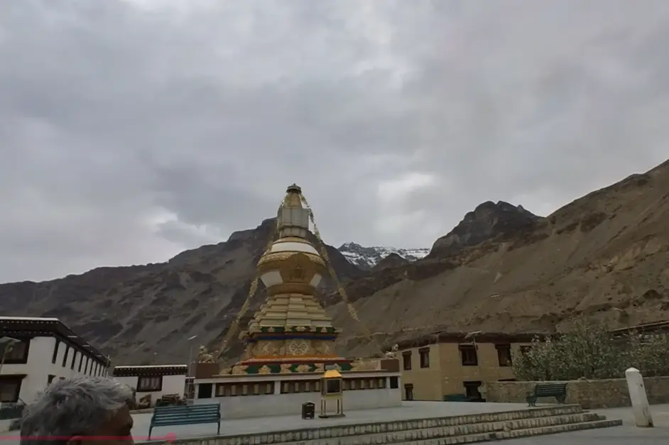 White and gold Buddhist stupa inside the Tabo Monastery complex against barren mountains.
