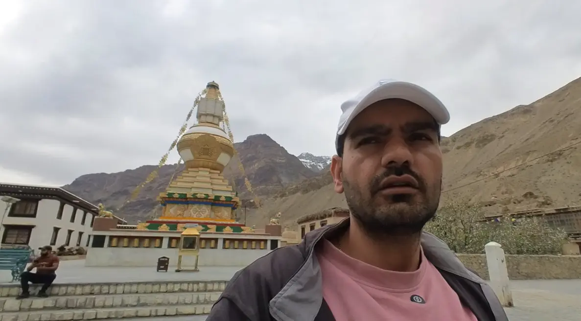 Naveen Kumar standing beside a white and gold stupa at Tabo Monastery.