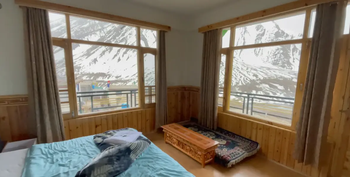Tara Guest House room with double bed, extra mattress and large windows facing snowy Pin Valley mountains