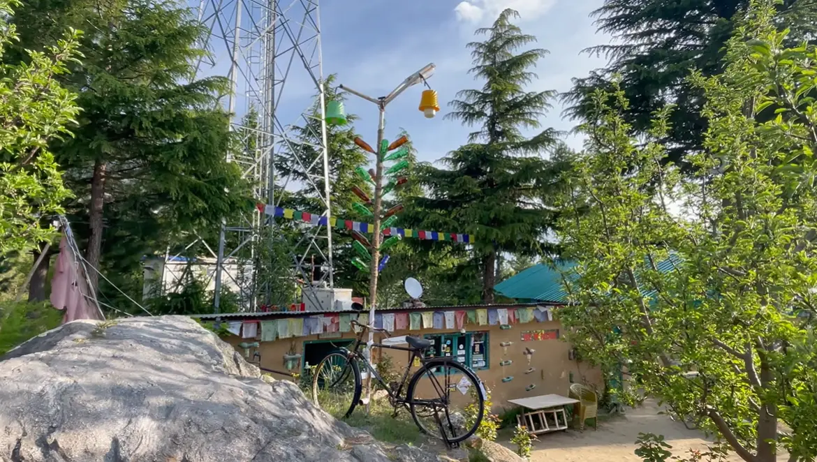 Trees, prayer flags, a bicycle and the outdoor grounds at The Monk in Kalpa