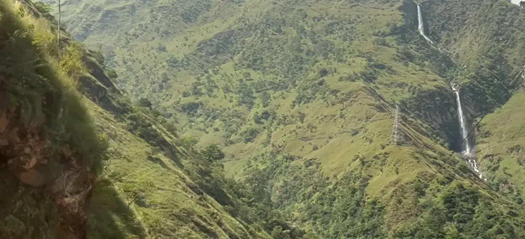 Tall waterfall on the green mountain road toward Adi Kailash