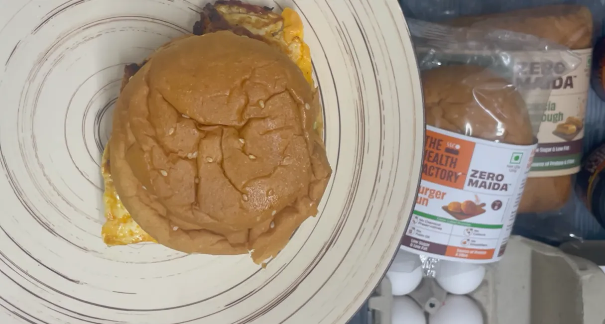Assembled egg avocado burger on a plate with the packaged bun visible beside it
