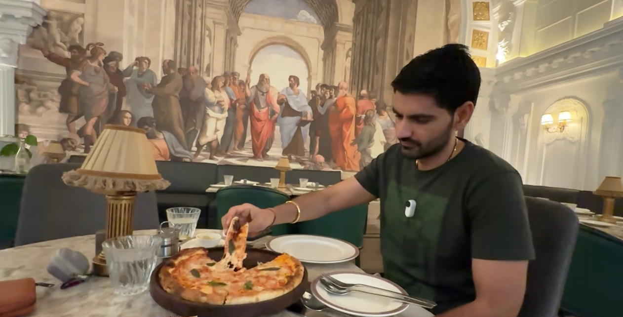 Creator lifting a slice of pizza inside Begeterre museum themed restaurant Gurgaon