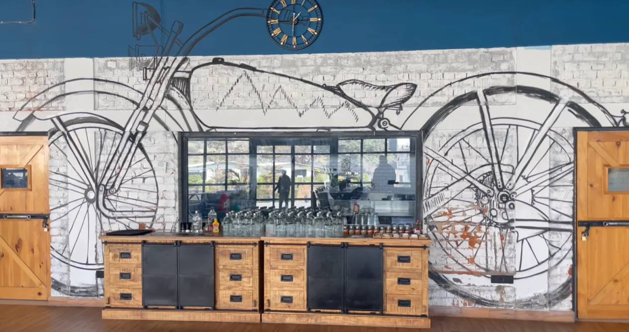 Large line drawing of a motorcycle on a brick wall inside The Biker's Barn