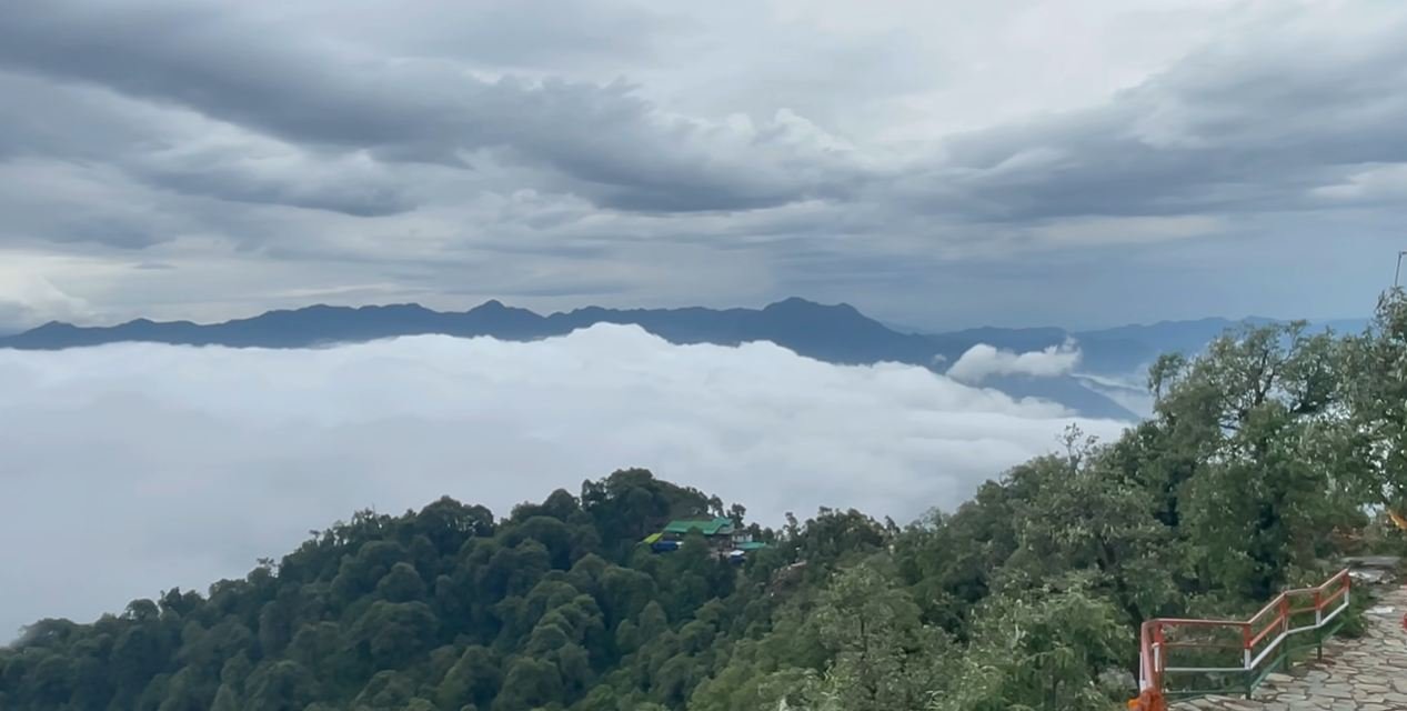 Low clouds over a forested valley beside the Kartik Swami trek