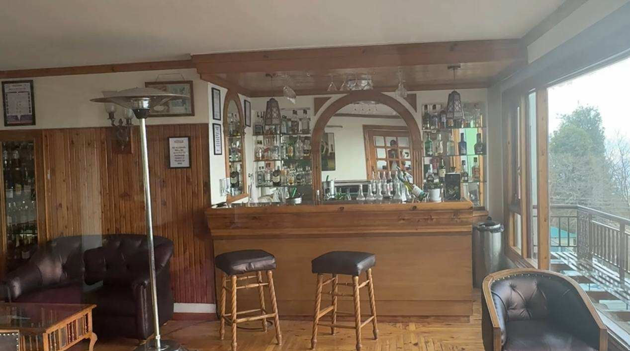 Wooden bar counter beside valley-facing windows at Club Mahindra Mashobra