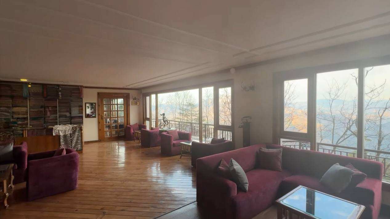 Wooden lounge with sofas and valley-facing windows at Club Mahindra Mashobra