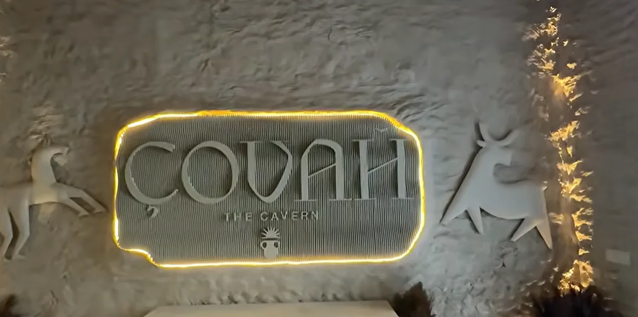 Illuminated Covah The Cavern sign on a textured cave-style wall in Gurgaon