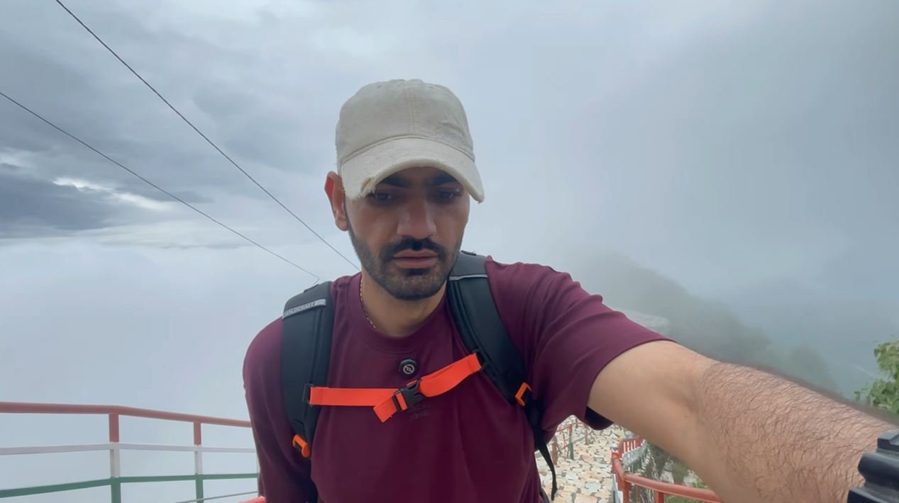 Naveen on the foggy Kartik Swami ridge wearing a backpack