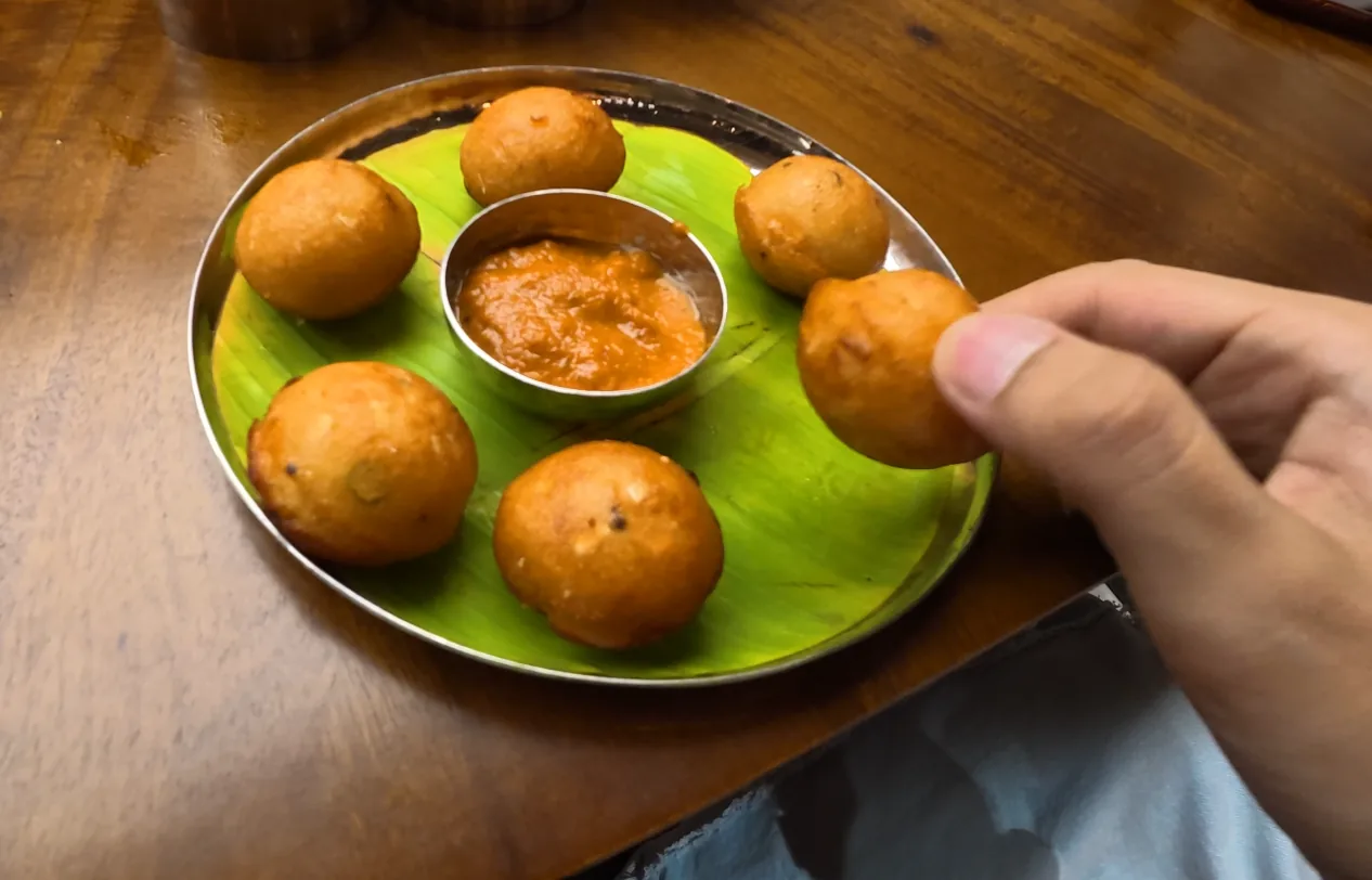 Small round paniyaram served with chutney on a banana-leaf-lined plate