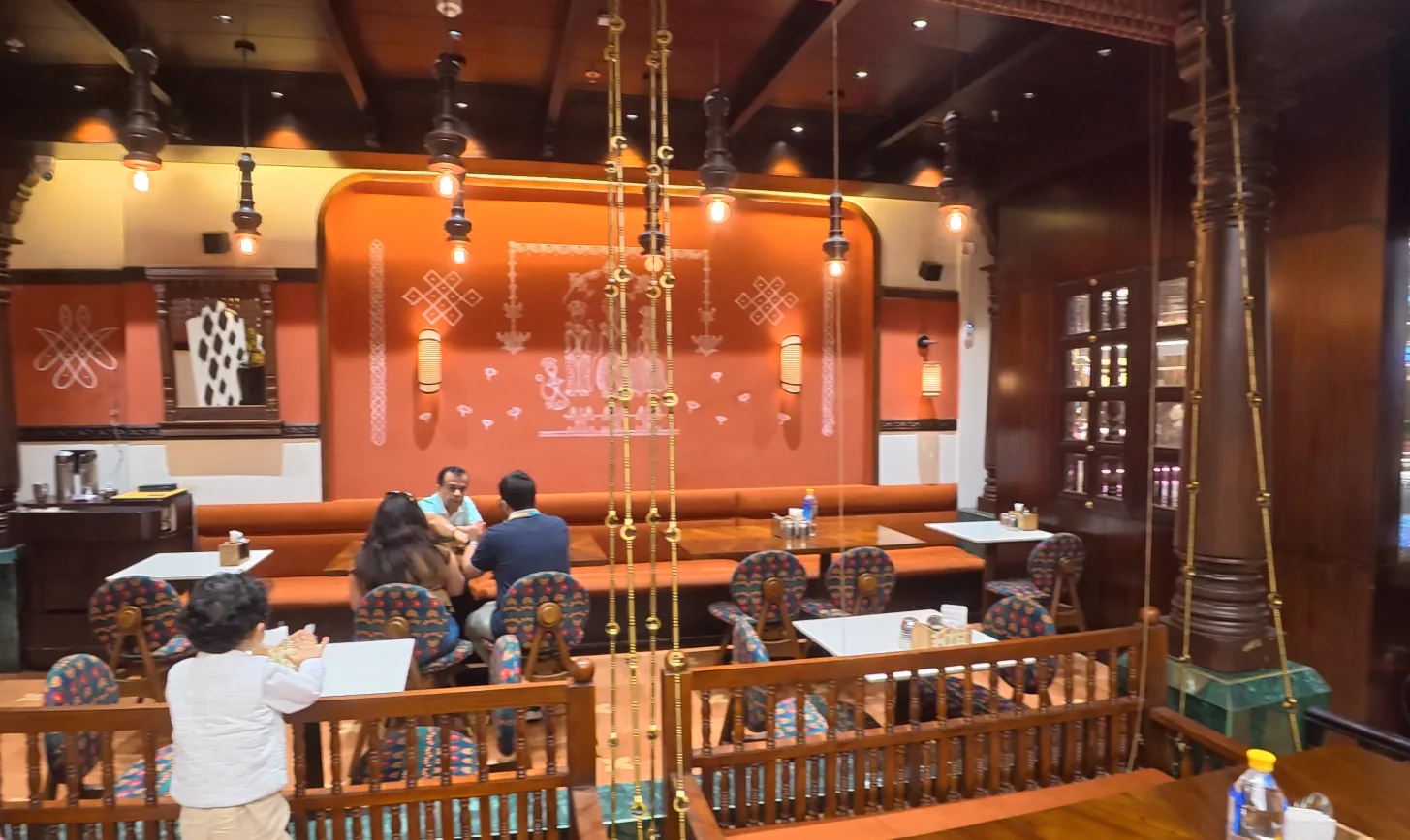 Dining area with orange seating and wooden details at Daksina Bhawan