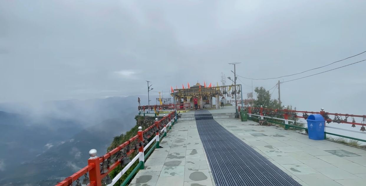 Paved walkway leading to Kartik Swami Temple through mist