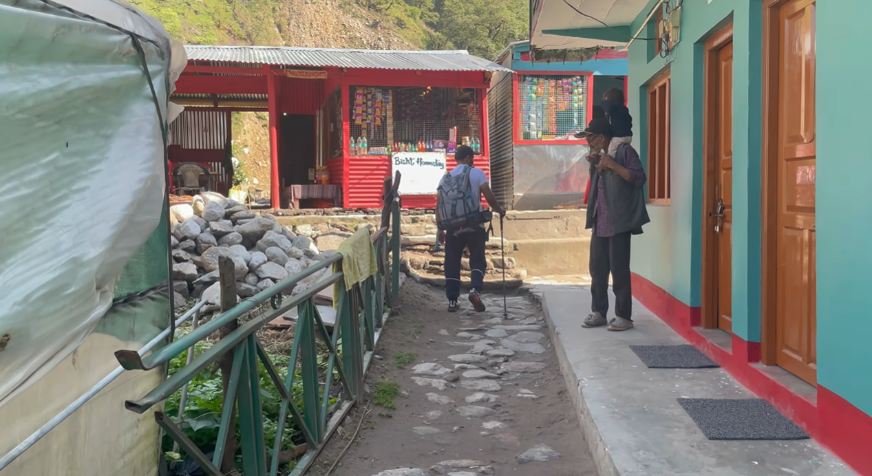 Stone path through Gaundhar village past homes and a small shop