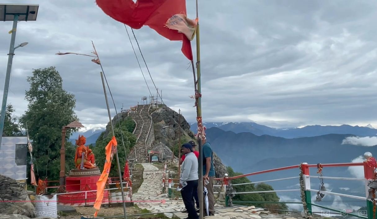 Stone steps, saffron flags and a Hanuman statue near Kartik Swami Temple