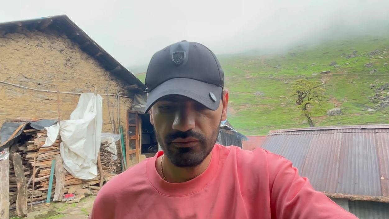 Creator outside the homestay with green mountain slope behind