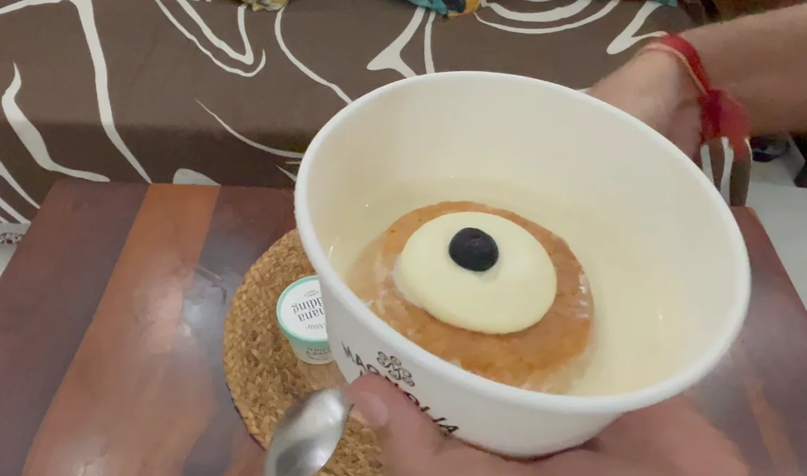 Tres leches in a Magnolia Bakery cup topped with cream and a blueberry