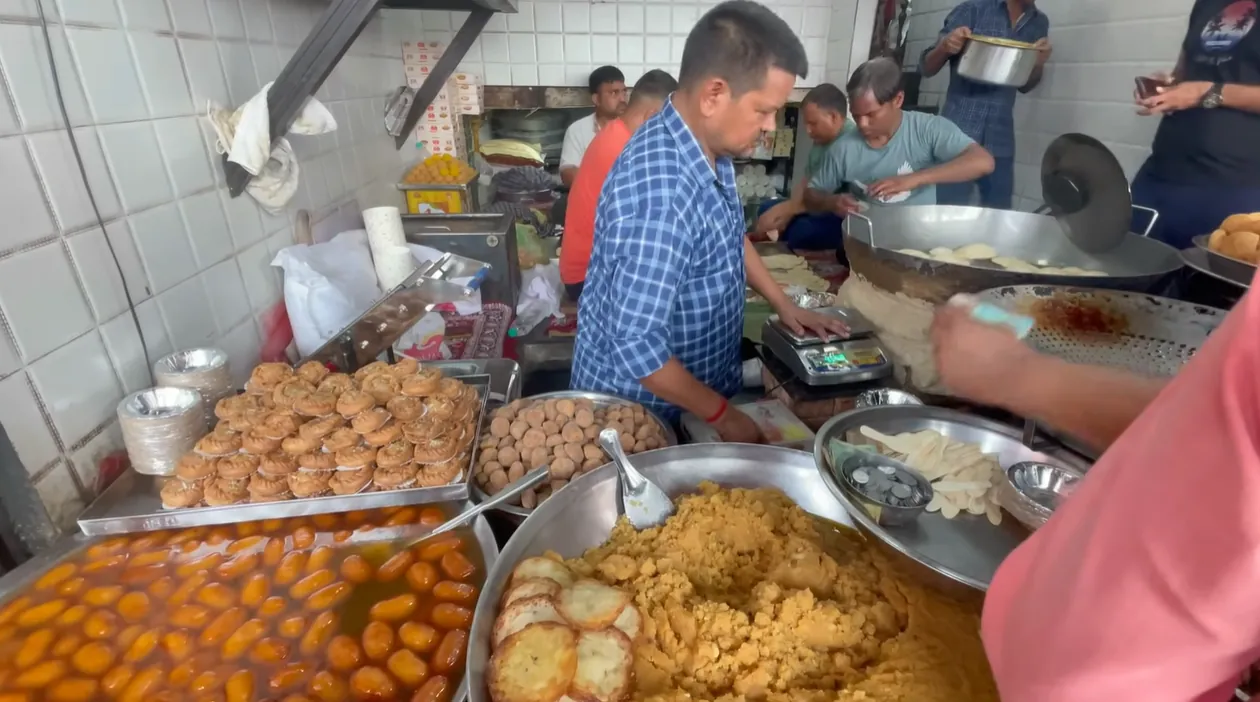 Workers preparing fried puris and sweets at the Mohan Ji Puri Wale counter