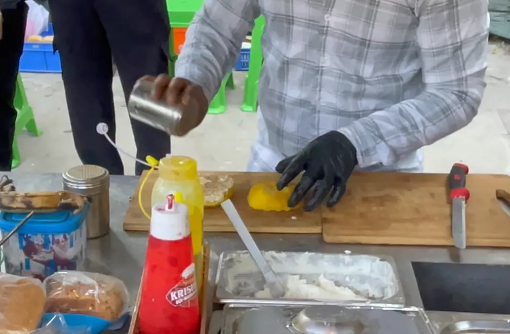 Vendor preparing a pineapple bun with makkhan at the cart