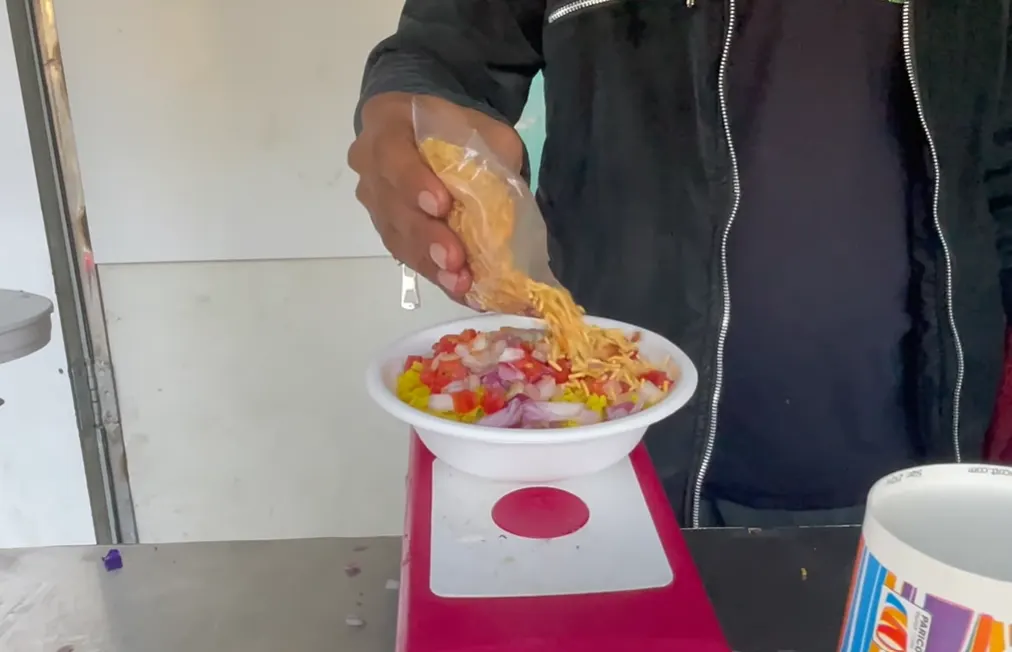 Sev being added to poha with chopped onion and tomato