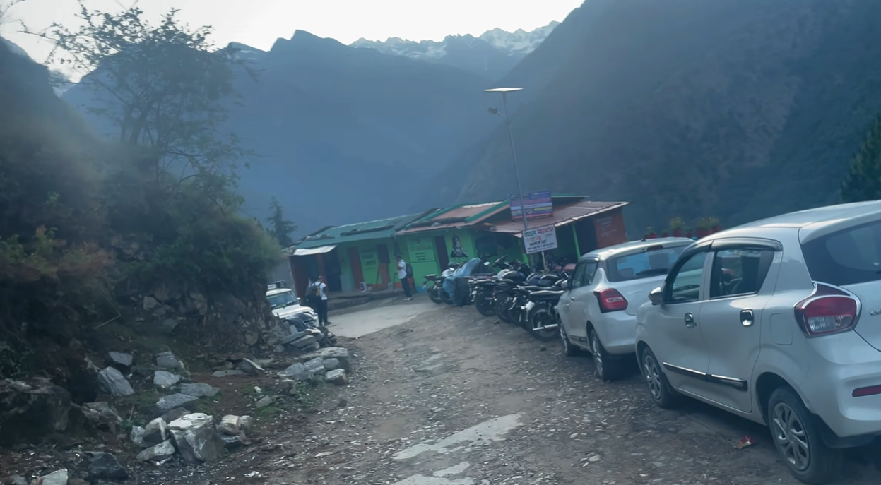 Cars and motorcycles parked at the Madmaheshwar trek starting point near Ransi