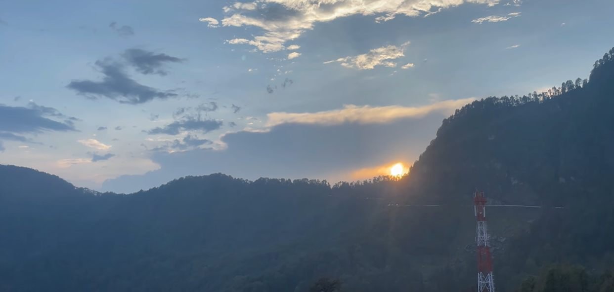 Sunset light beyond a dark ridgeline near Chopta