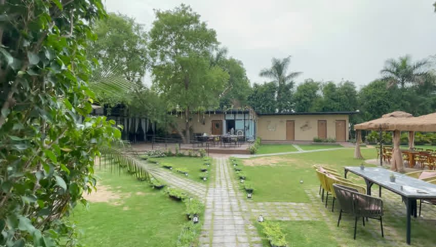 Wide lawn with outdoor tables and cabanas at The Sunroom Gurgaon