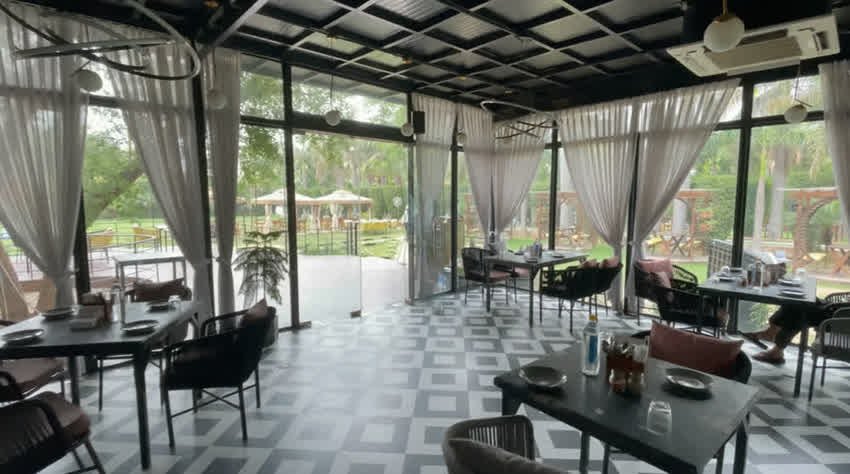 Glass-walled indoor dining room overlooking the garden at The Sunroom