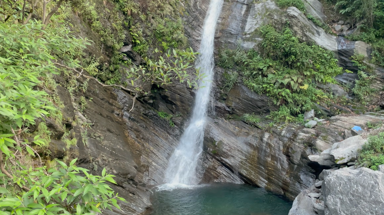 Waterfall dropping into a rocky pool beside the Madhyamaheshwar trail